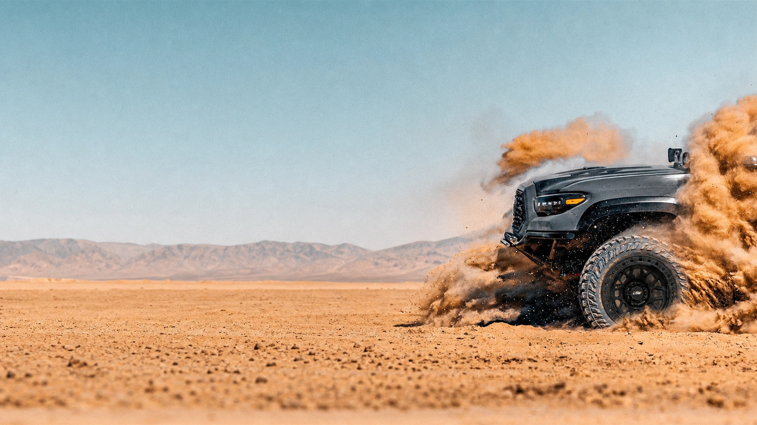 Off-road vehicle with black LSW wheels crossing the desert