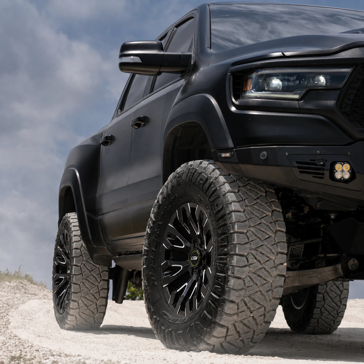 Low angle close-up of a raised black off-road pickup truck equipped with LSW black off-road forged wheels